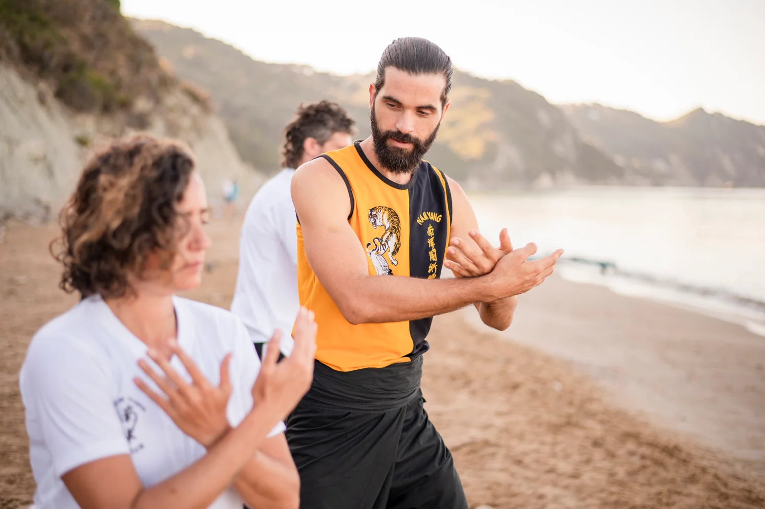 Thomas Croc guiding a student through a Chi Kung hand movement on the beach